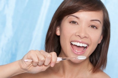 Smiling woman brushing her teeth, Group Dental Insurance